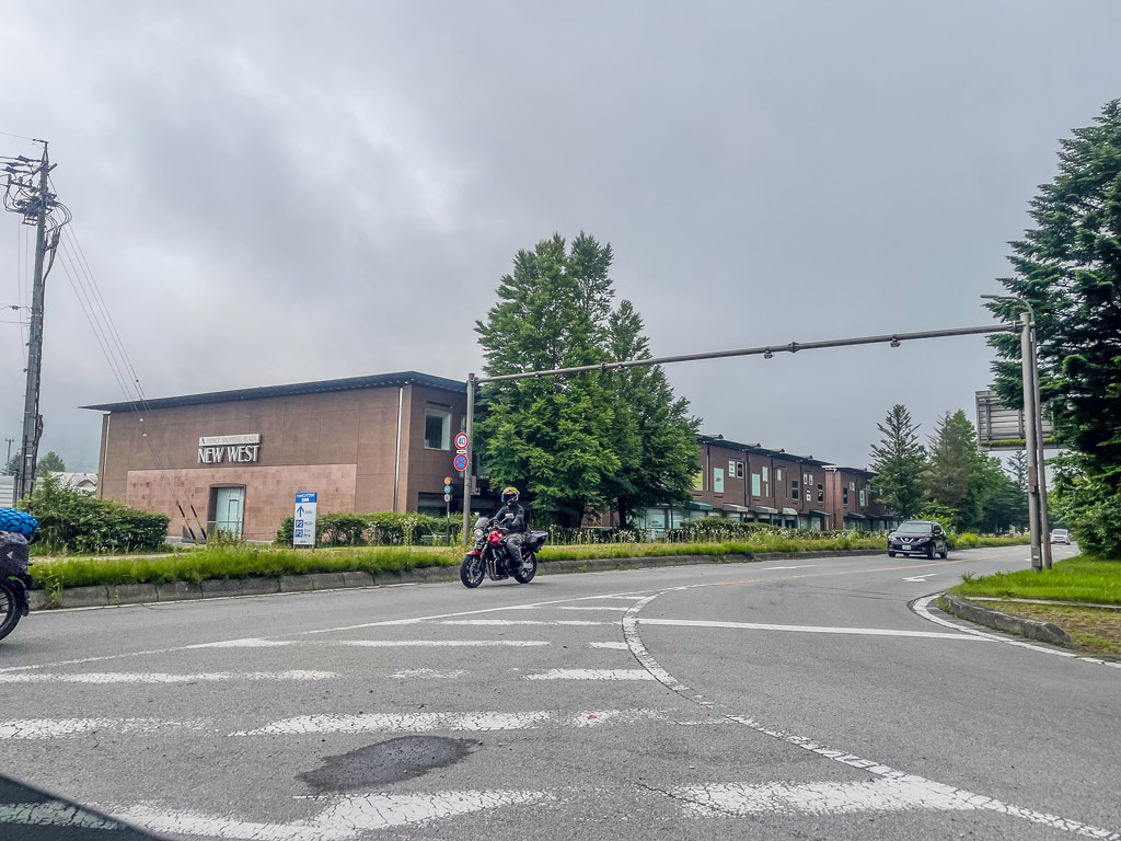 軽井沢NEW WEST前の道路とバイクで走り抜けるライダー