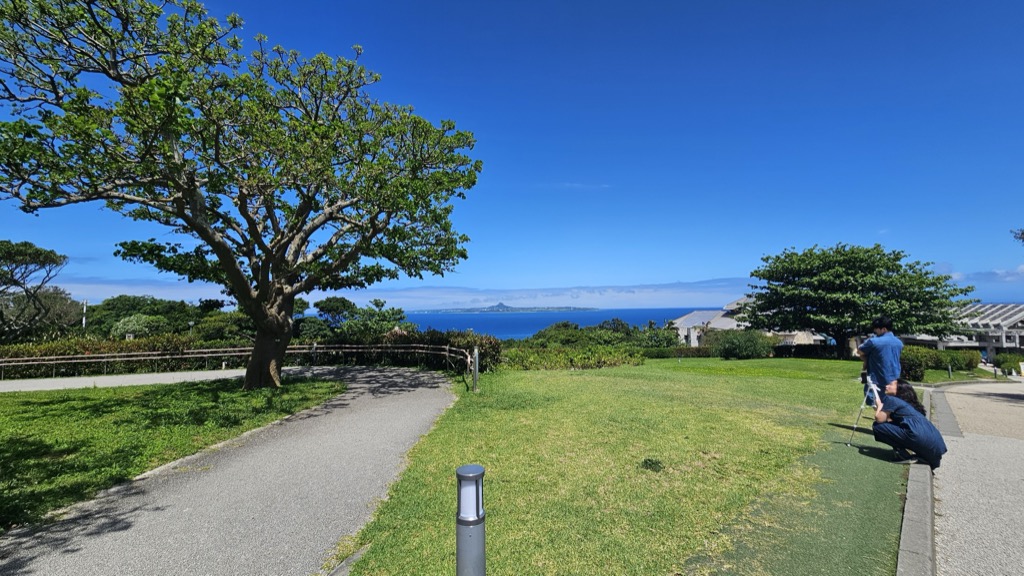 海洋博公園の芝生広場から望む伊江島とエメラルドブルーの海 美ら海水族館訪問前の澄み切った眺め