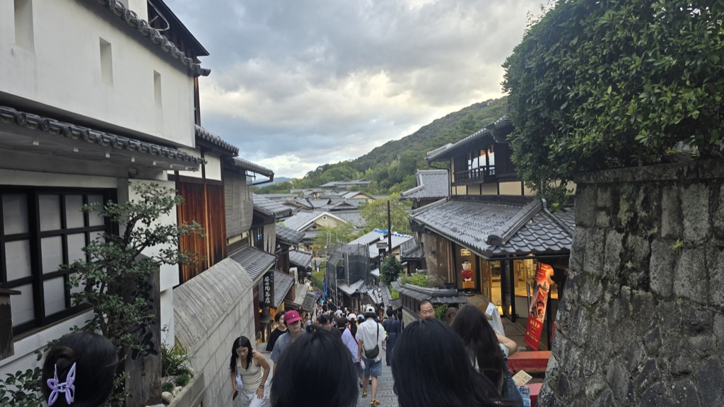 三年坂の石畳を歩く観光客 瓦屋根と木造町家の夕暮れの町並み