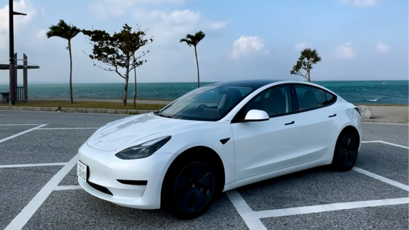 沖縄の海沿いに停まる白いTesla Model 3